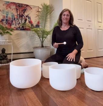 Woman sitting in a room on the floor with crystal bowls
